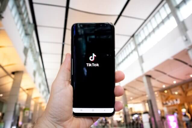 person holding phone in mall showing the TikTok app